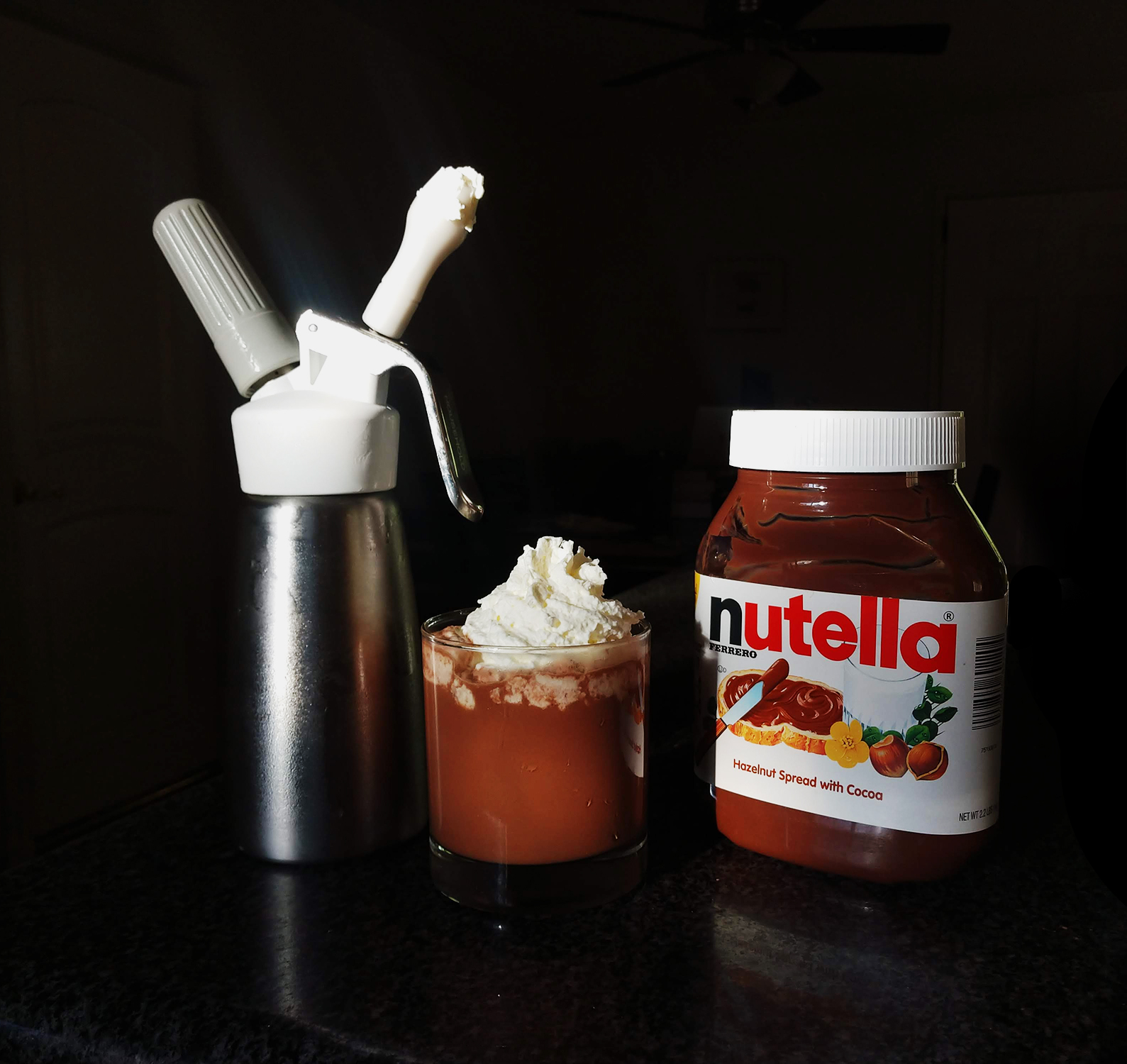 A whipped cream canister, a nutella latte with whipped cream, and a jar of nutella.