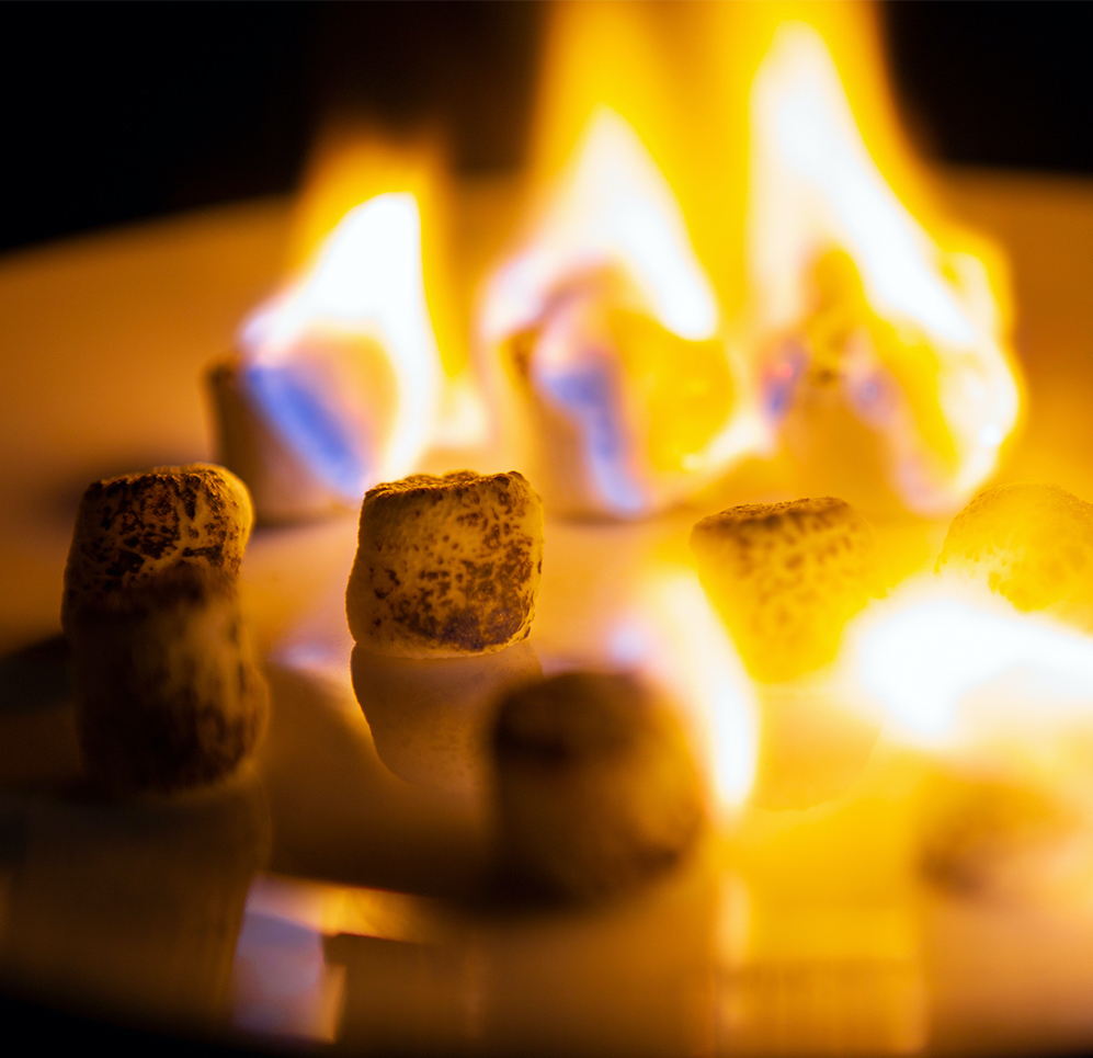 Toasted mini marshmallows on a plate with some still in flames.